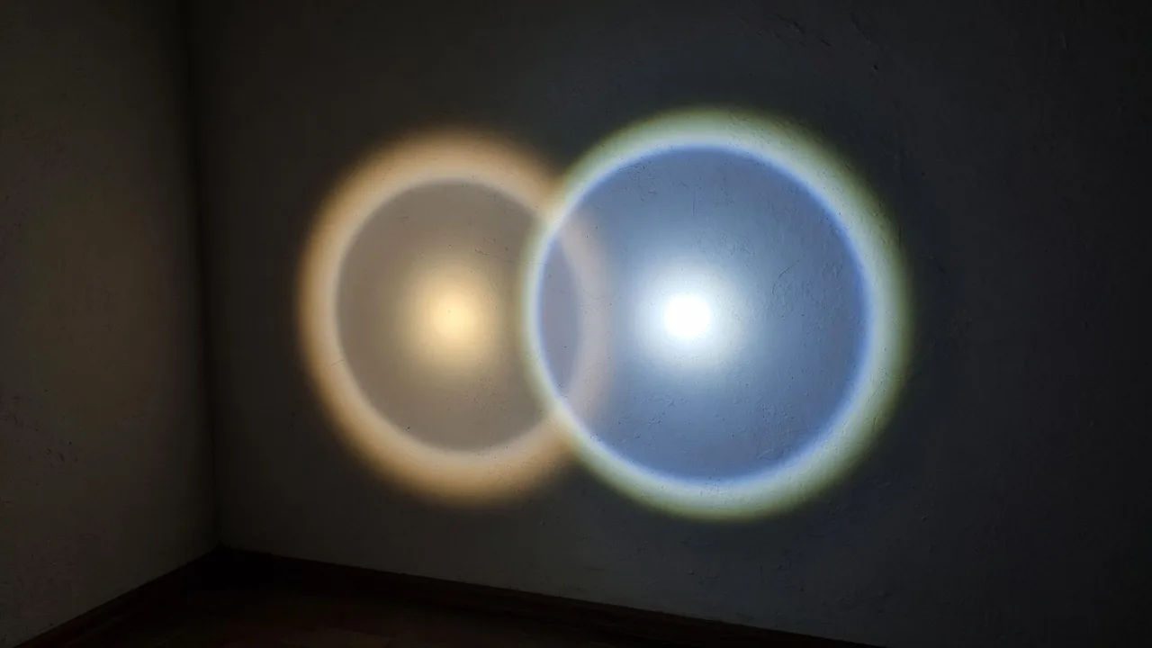 Two flashlight beams side by side on a dark plaster wall, the left dimmer with soft edges and the right brighter with a defined hotspot.